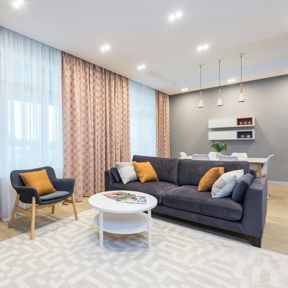Modern gray sectional sofa with orange throw pillows and wooden legs in a stylish living room