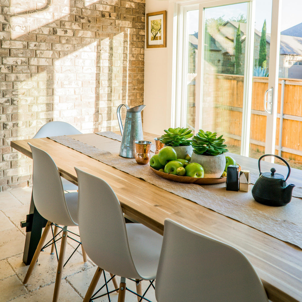 Wooden dining table with white chairs and green succulents in a modern dining room setting